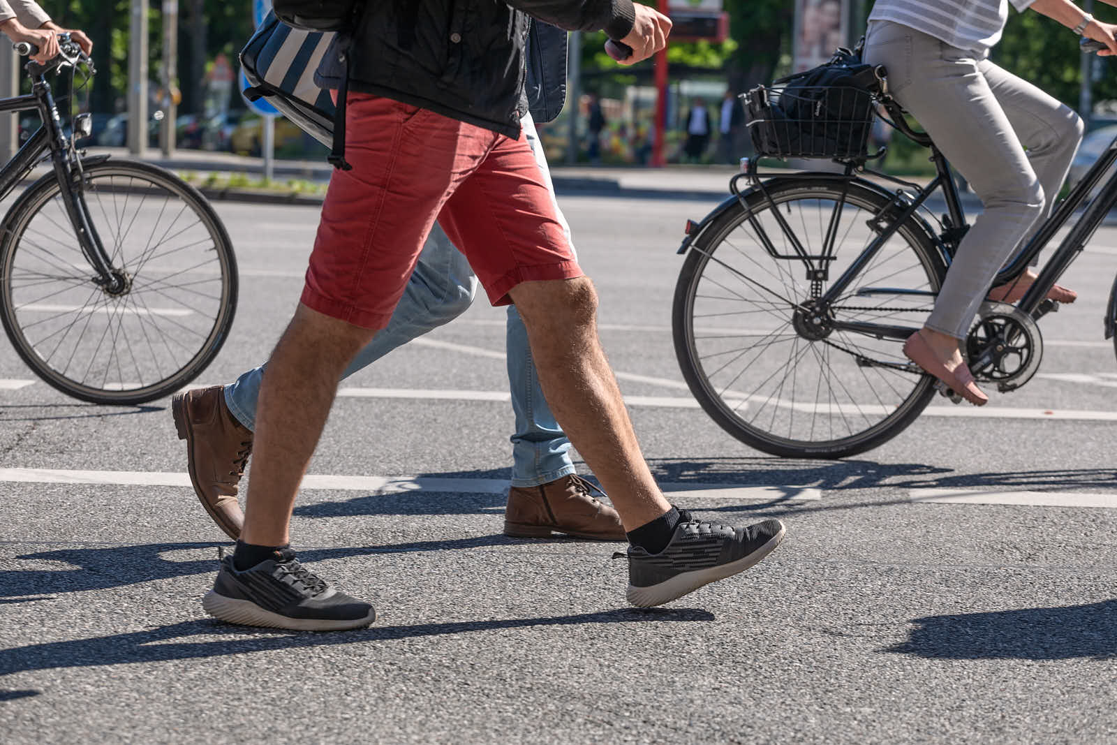Menschen in laufen zu Fuss durch das Bild, im Hintergrund fahren zwei Radfahrer.