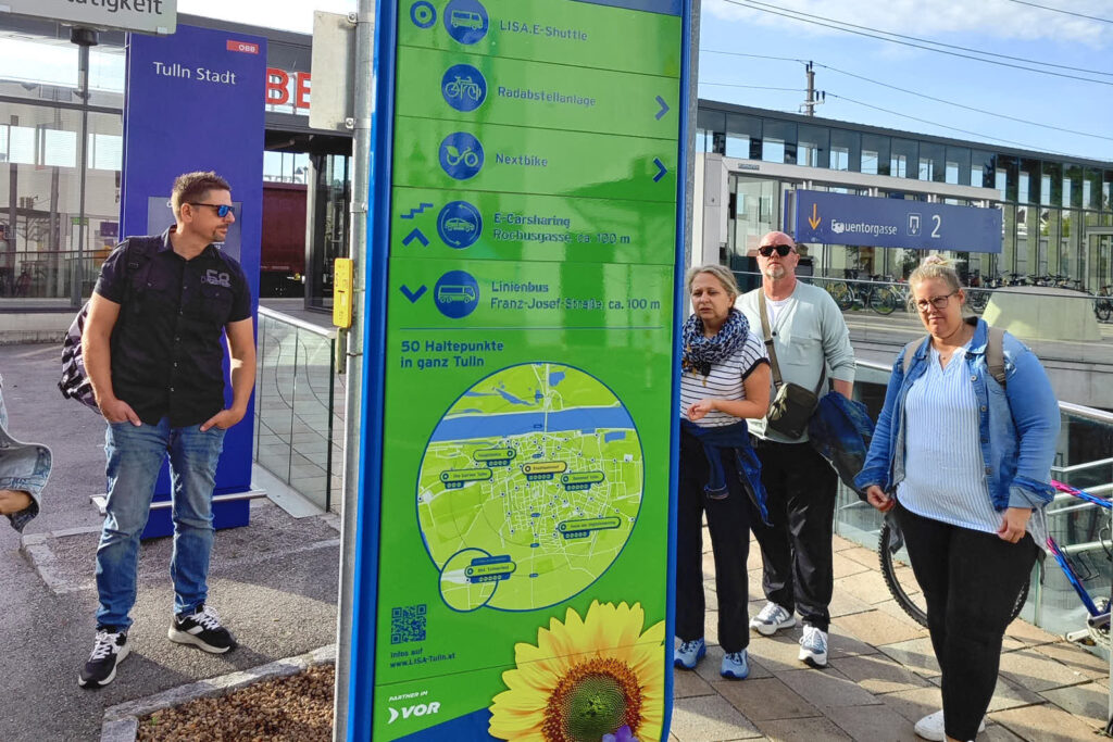 Infosäule der Lisa Mobilitätstation beim Bahnhof. Hinweis zu LISA E-Shuttle, Radabstellanlage, Nextbike, E Carsharing und Linienbus inkl. Orientierungsplan