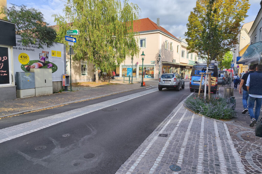 Straße Im Ortsgebiet von Tulln, z.T mit Bäumen begrünt. Mit einer Spur Pflastersteine (eben verbaut) ist ein Radweg gegen die Einbahn getrennt