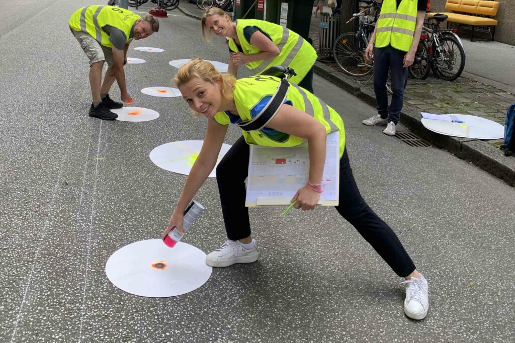 Kaiserfeldgasse auf der Straße, Drei Personen mit Warnweste haben eine Sprühdose in der Hand und Sprühen Punke auf die Fahrbahn.