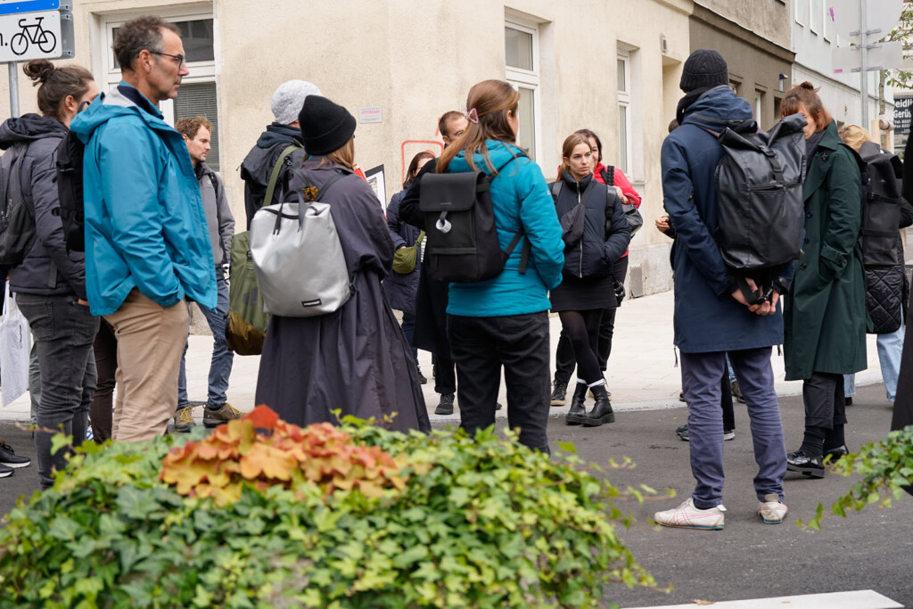 Transformatorinnen Workshop Gruppe steht auf der Straße und lauscht gespannt der/dem Vortragenden.