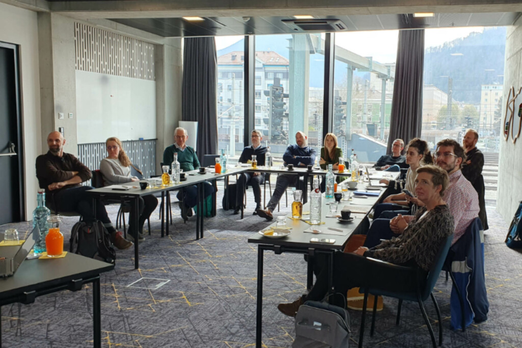 Menschen sitzen an einem U-förmigen Besprechungstisch