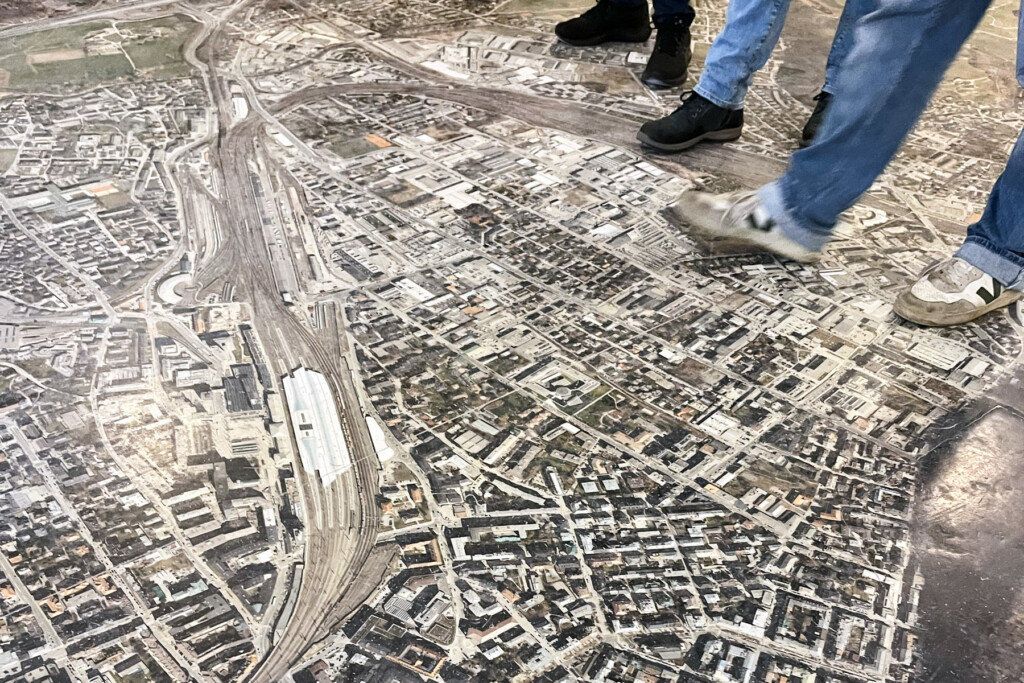 Mehrere Personen (Beine/Schuhe sind zu sehen) stehen am großen Bodenplan des Stadtteils Schallmoos.