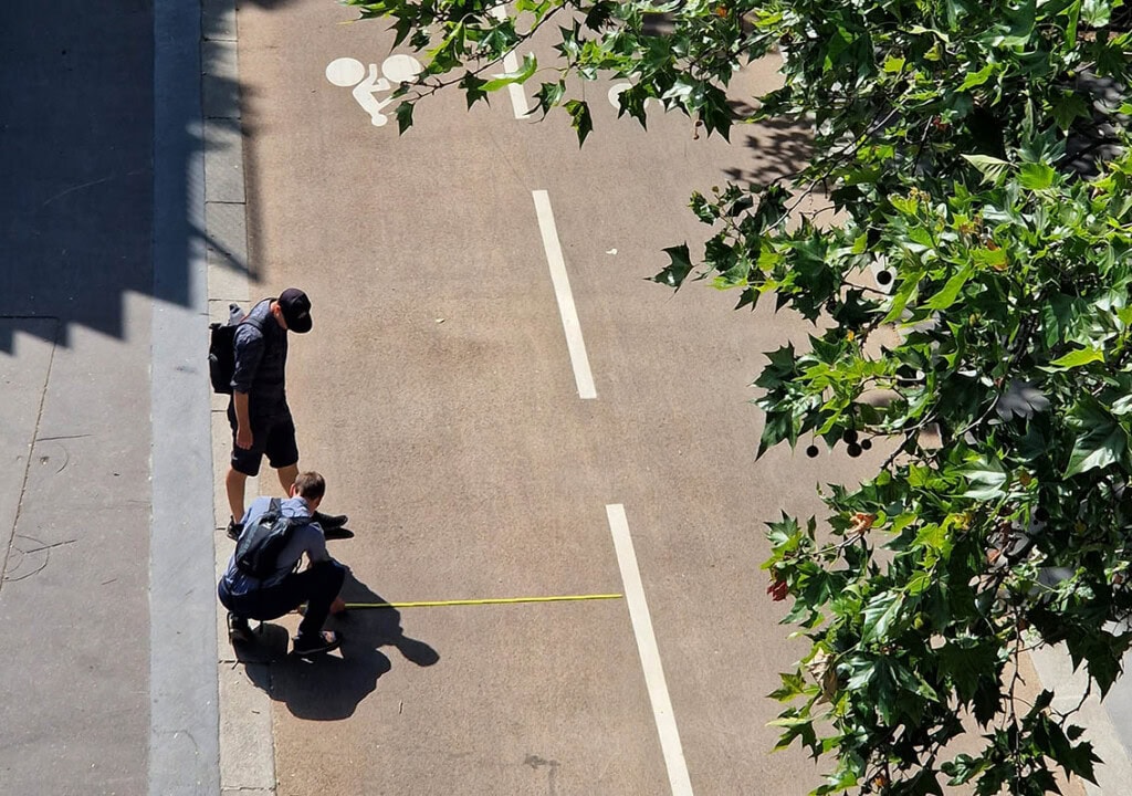 Sicht von oben auf einen Radweg, der von zwei Personen abgemessen wird