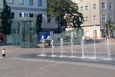 Foto von Asphaltfläche in Wien mit Wasserspielen in sommerlicher Hitze