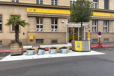 Foto einer temporären Umgestaltung einer Straße vor einer Post Bank99 mit Pflanztrögen