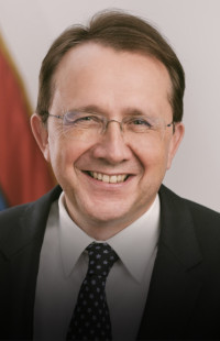Portrait Bürgermeister Matthias Stadler, Bürgermeister St.Pölten. Dunkle Haare, dünnrandige Brille, schwarzes Sakko, Krawatte. Lächelt sehr sympathisch