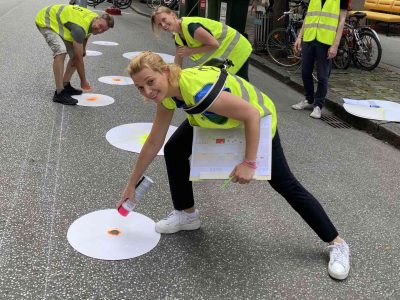 Kaiserfeldgasse auf der Straße, Drei Personen mit Warnweste haben eine Sprühdose in der Hand und Sprühen Punke auf die Fahrbahn.