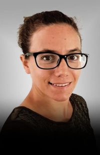 Portrait Cornelia Hebenstreit. Junge Frau dunkelhaarig, mit schwarzer Brille und schwarzer Bluse