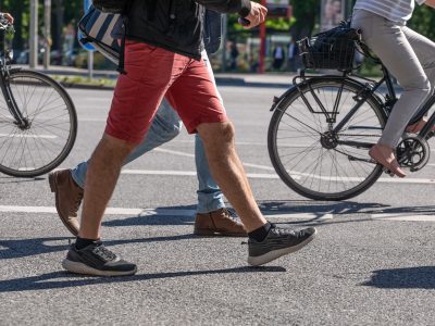 Menschen in laufen zu Fuss durch das Bild, im Hintergrund fahren zwei Radfahrer.